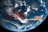 A satellite view of the Australian continent and a reddish plume flowing over the ocean from the east coast