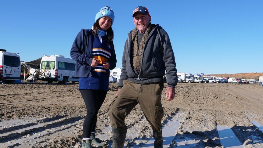 man and woman standing in the mud