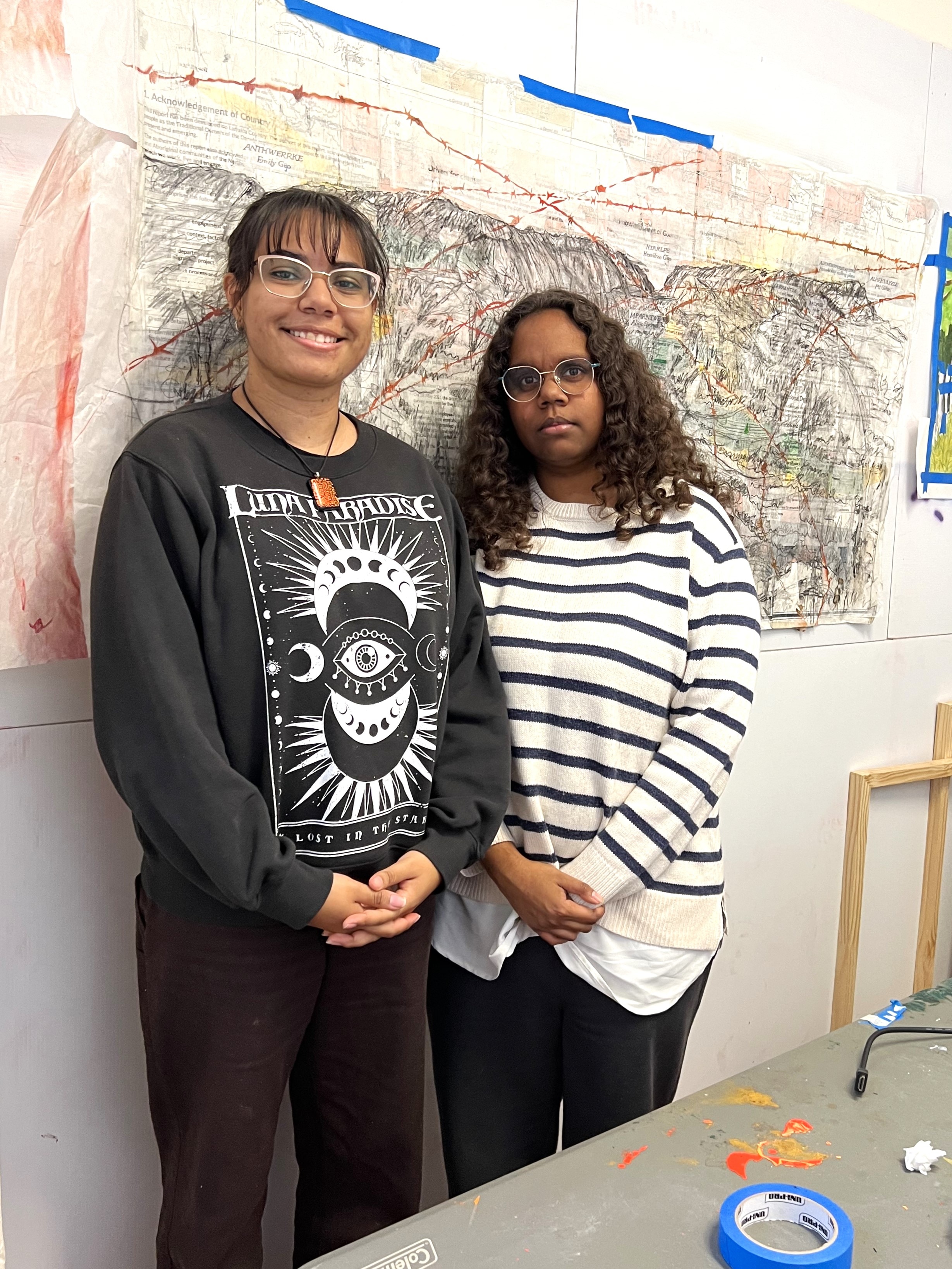 A young women stand around art and sketches