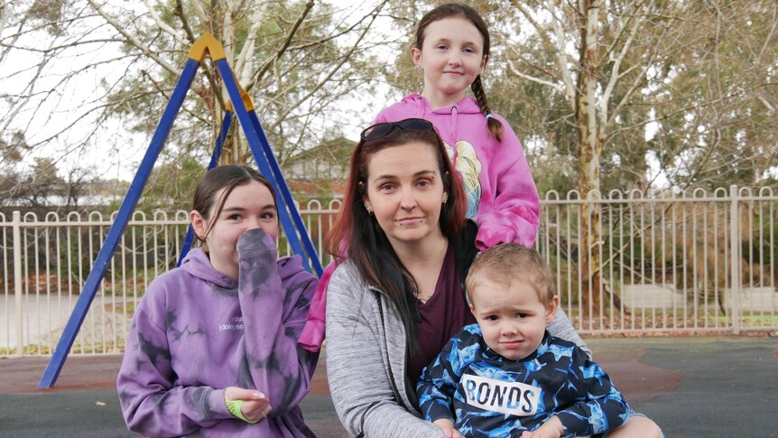 A woman with her three children sitting in playground.