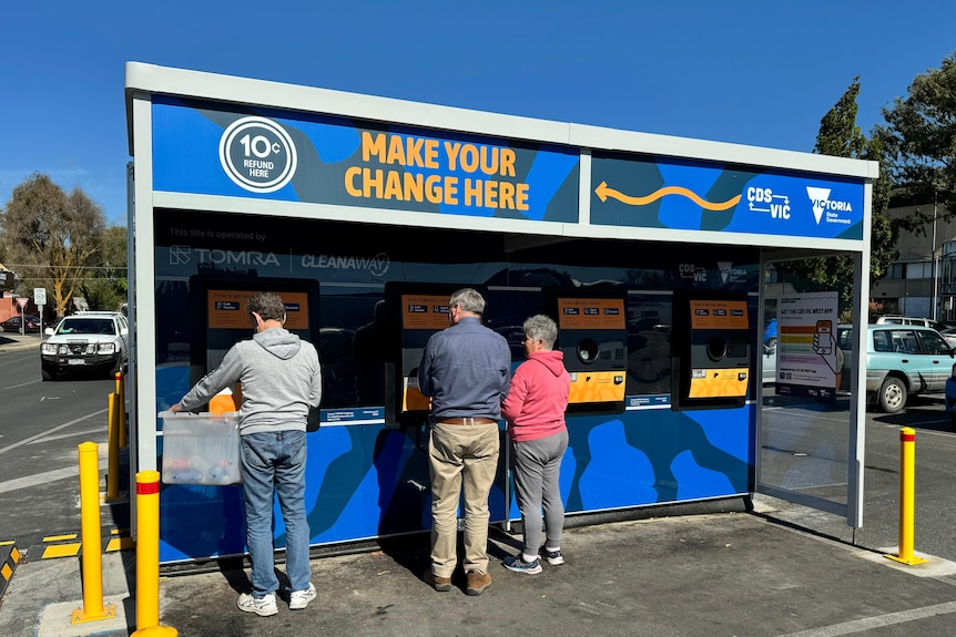 People stand at a container deposit station.