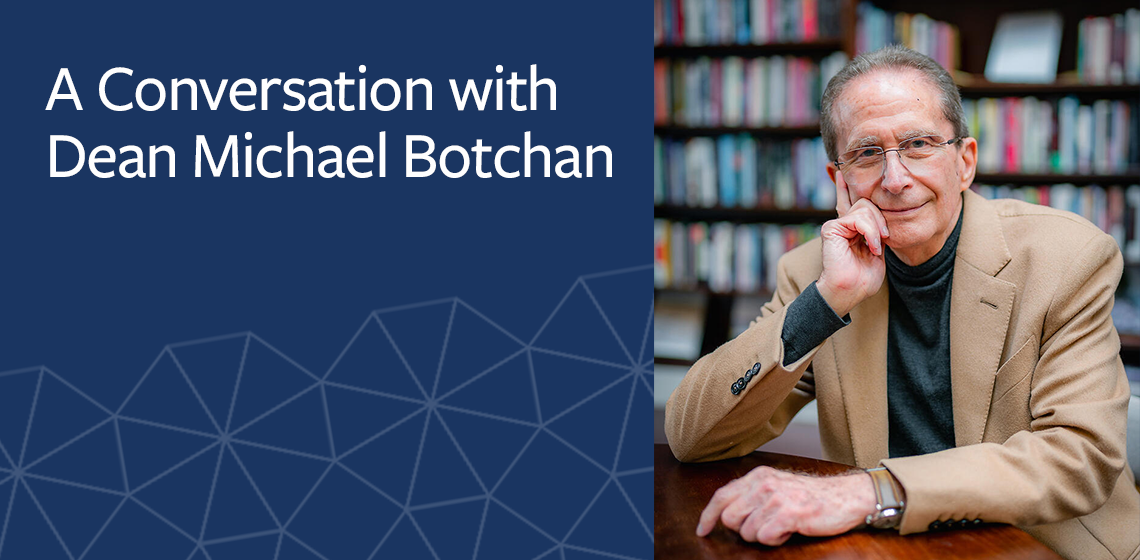 Headshot of Michael Botchan; man in camel sportsjacket and dark turtleneck sitting in an atrium