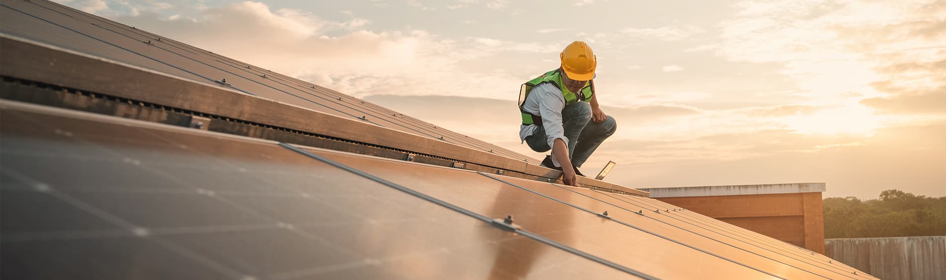 A solar technician inpects solar panels on an industrial rooftop.