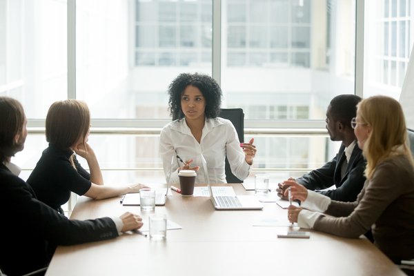 A businessperson at the head of a table leading a meeting.