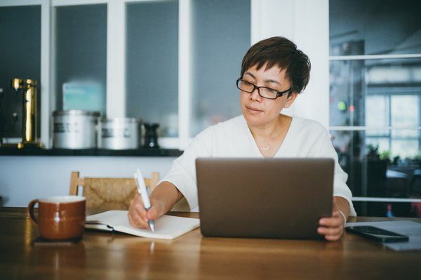 Person takes notes while sitting at table at home.