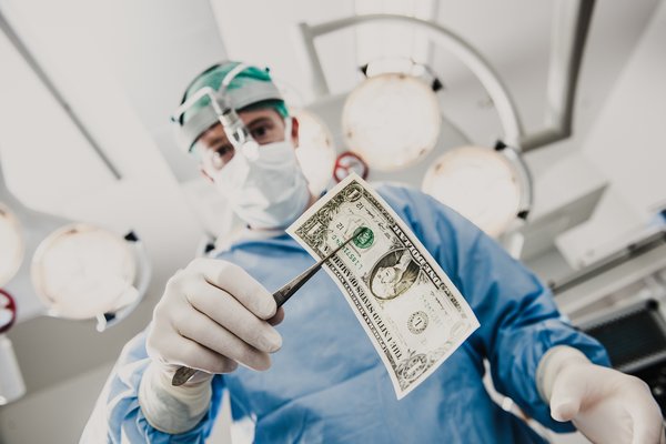 A surgeon holding a dollar bill with surgical forceps