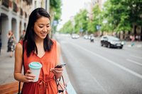 Woman holding her smartphone and a coffee