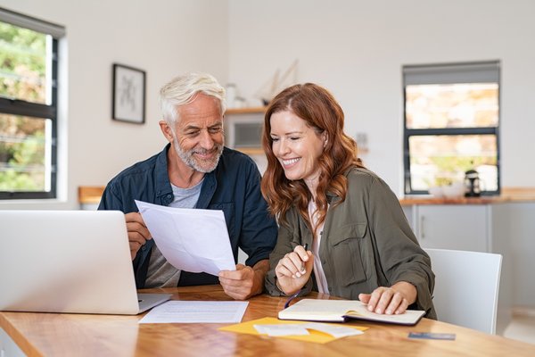 Two people smiling and looking at document.