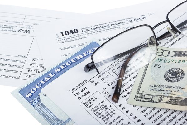 A W2, 1040 form, social security card, twenty dollar bill, and reading glasses.