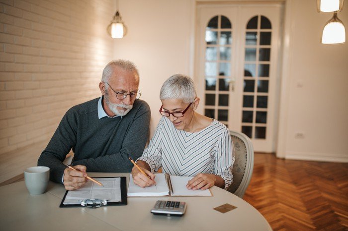 An older couple looking at documents at their kitchen table