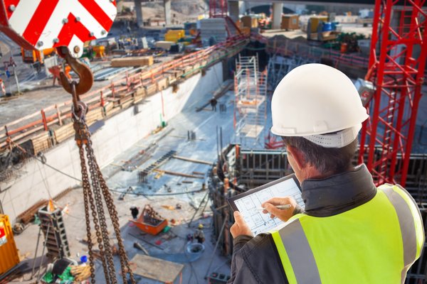 A person wearing a hard hat looking down into a building construction site.