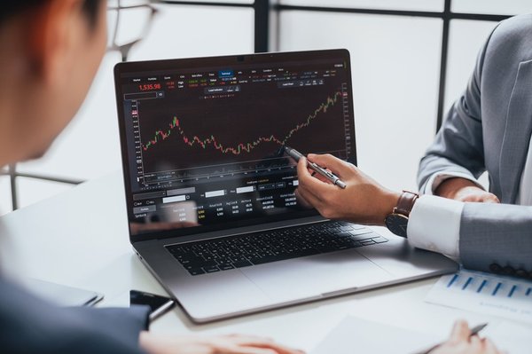 A business person pointing at a graph on a laptop.