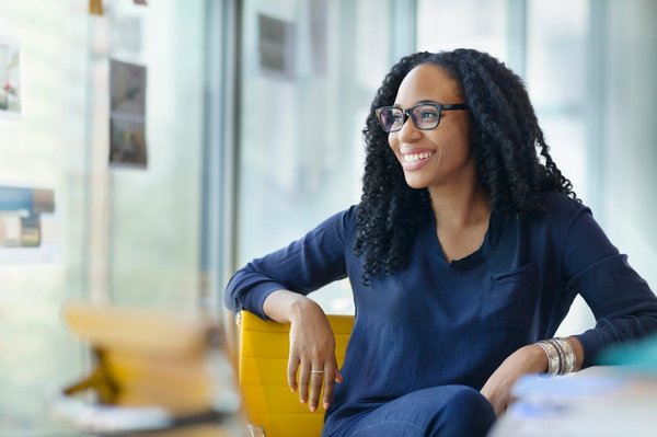 Individual saver smiling while seated in yellow chair in home office.