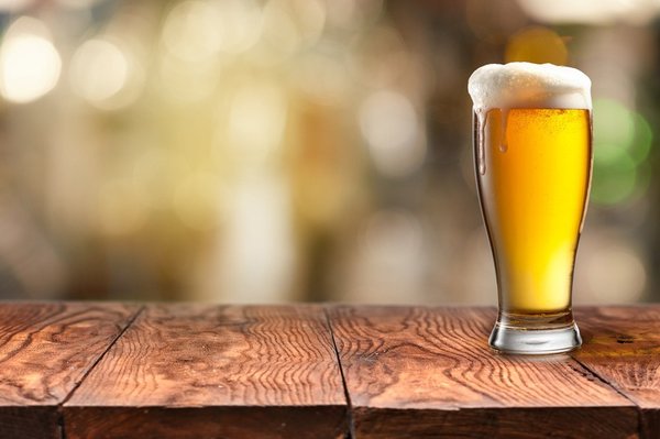 A glass of beer sitting on a table.