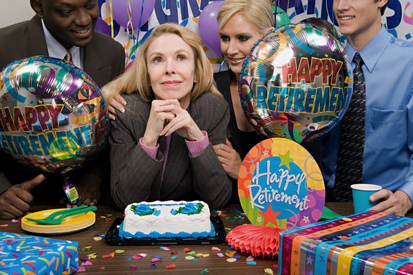 Office workers surround retiree at retirement party.