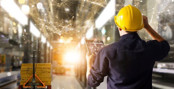 A person in a warehouse holding a tablet with superimposed graphics displaying connective technology in use.