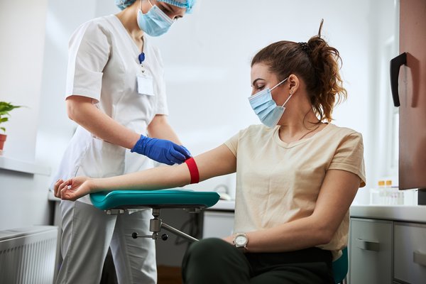 Person wearing mask and sitting in wheelchair receives medical treatment in hospital.