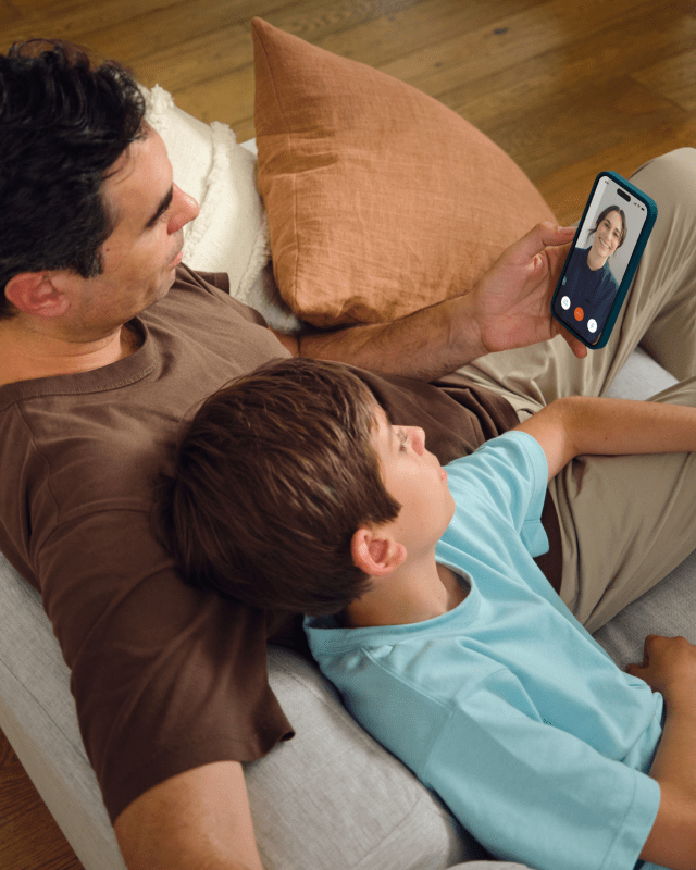 Father and son talking with a clinician via video chat on a smartphone