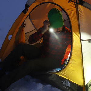 camper sitting in his tent using a flashlight