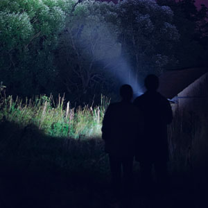 people on a night walk with flashlight guiding their path