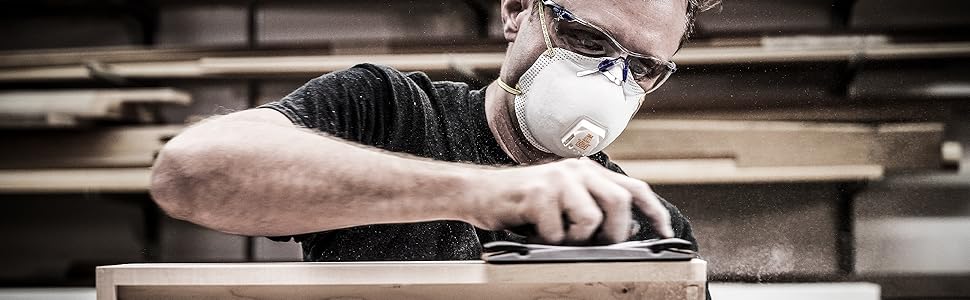 Man sanding drawer while wearing respirator