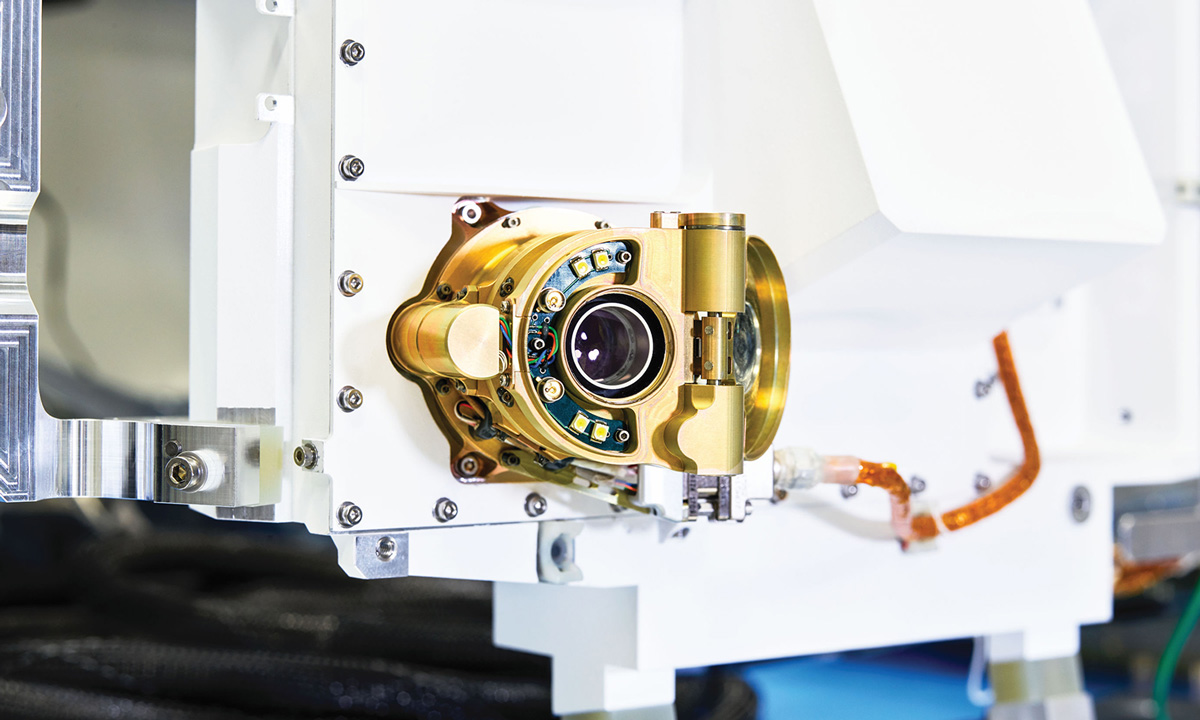 A small camera sits in gold-color housing on a white rover body.