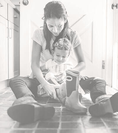 Mother and daughter sitting on a natural stone floor in their kitchen. 