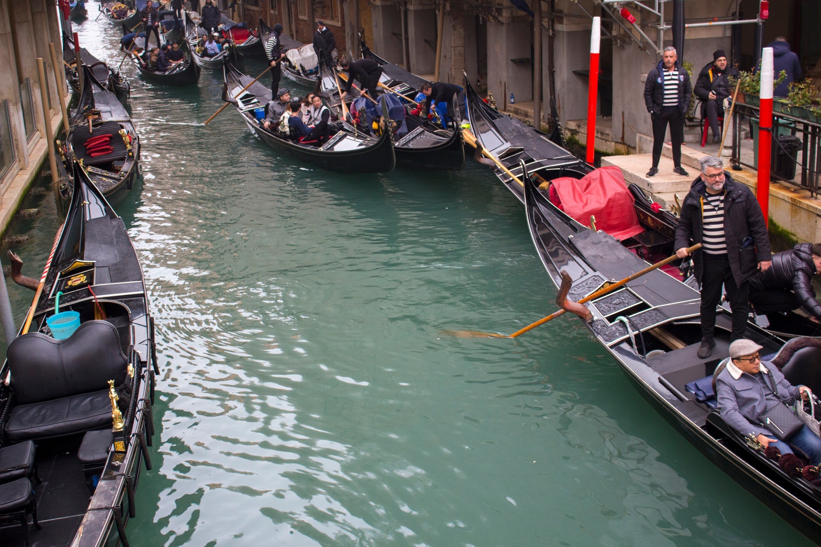 View of gondola tourist traffic on a narrow canal in Venice Italy.