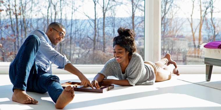 Couple playing a board game in their home, on the floor