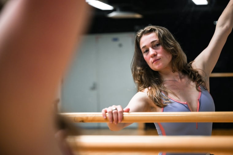 Ayla O'Day looks into a mirror while holding the barre in a dance studio