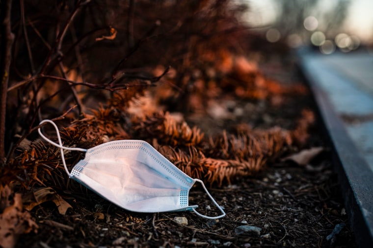 A discarded face mask on the side of the road on the dirt