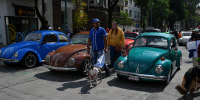 People walk past vintage Volkswagen Beetles, known in Mexico as "vochos," in Mexico City