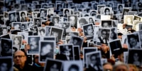 Relatives of victims hold pictures in the air.