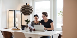 Image: Lesbian couple discussing financial bills over laptop while sitting at table