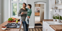 Father and son using tablet in kitchen looking at ceiling lamp