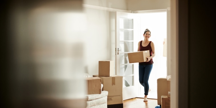 Image: Woman carrying boxes into her new home.