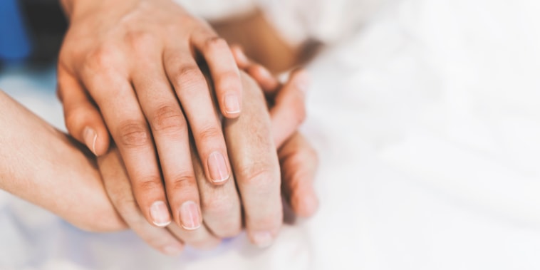 Cropped image of nurse holding man's hand