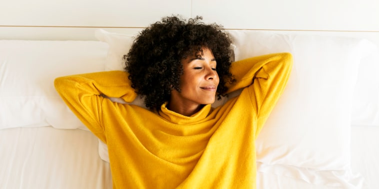 Smiling woman with closed eyes lying on bed