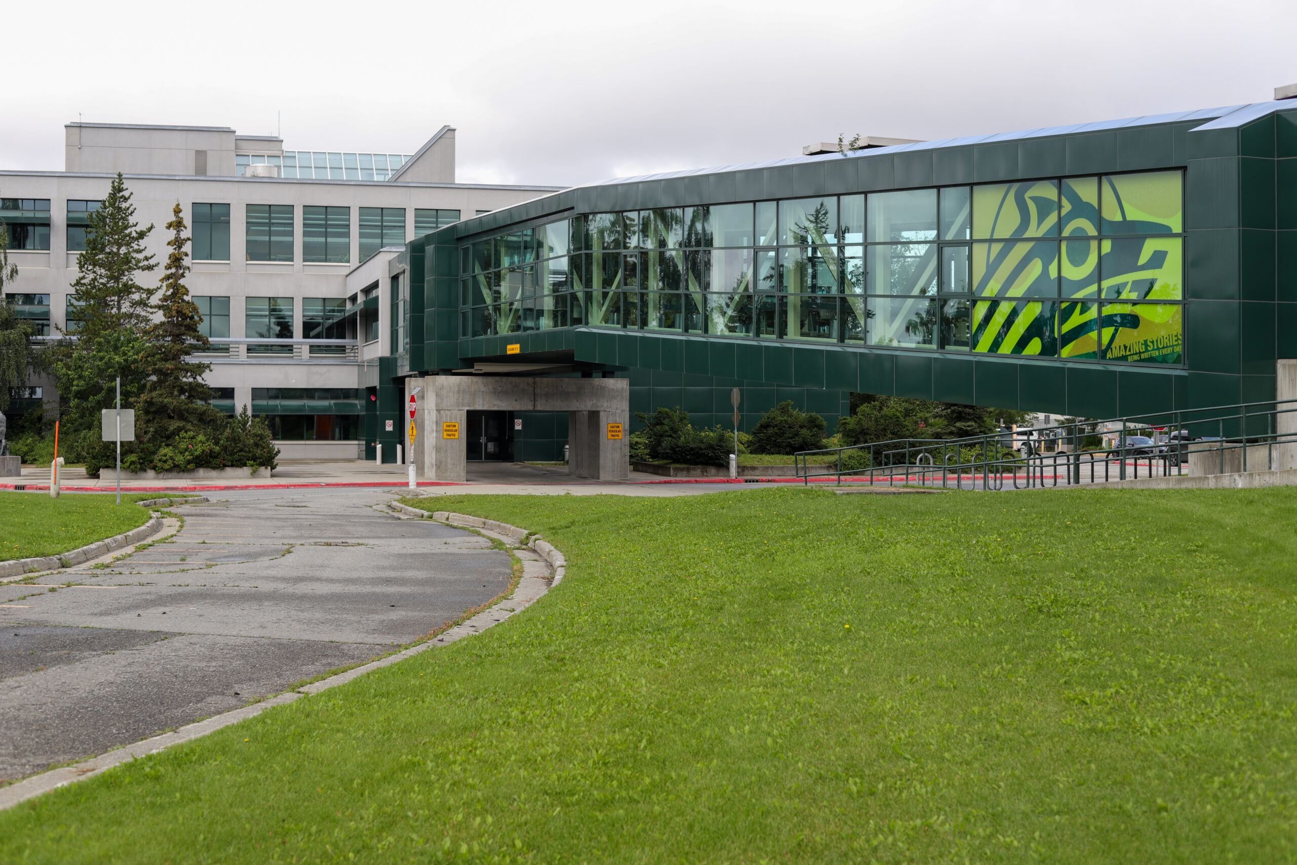 A lawn with an elevated pedestrian walkway over it.