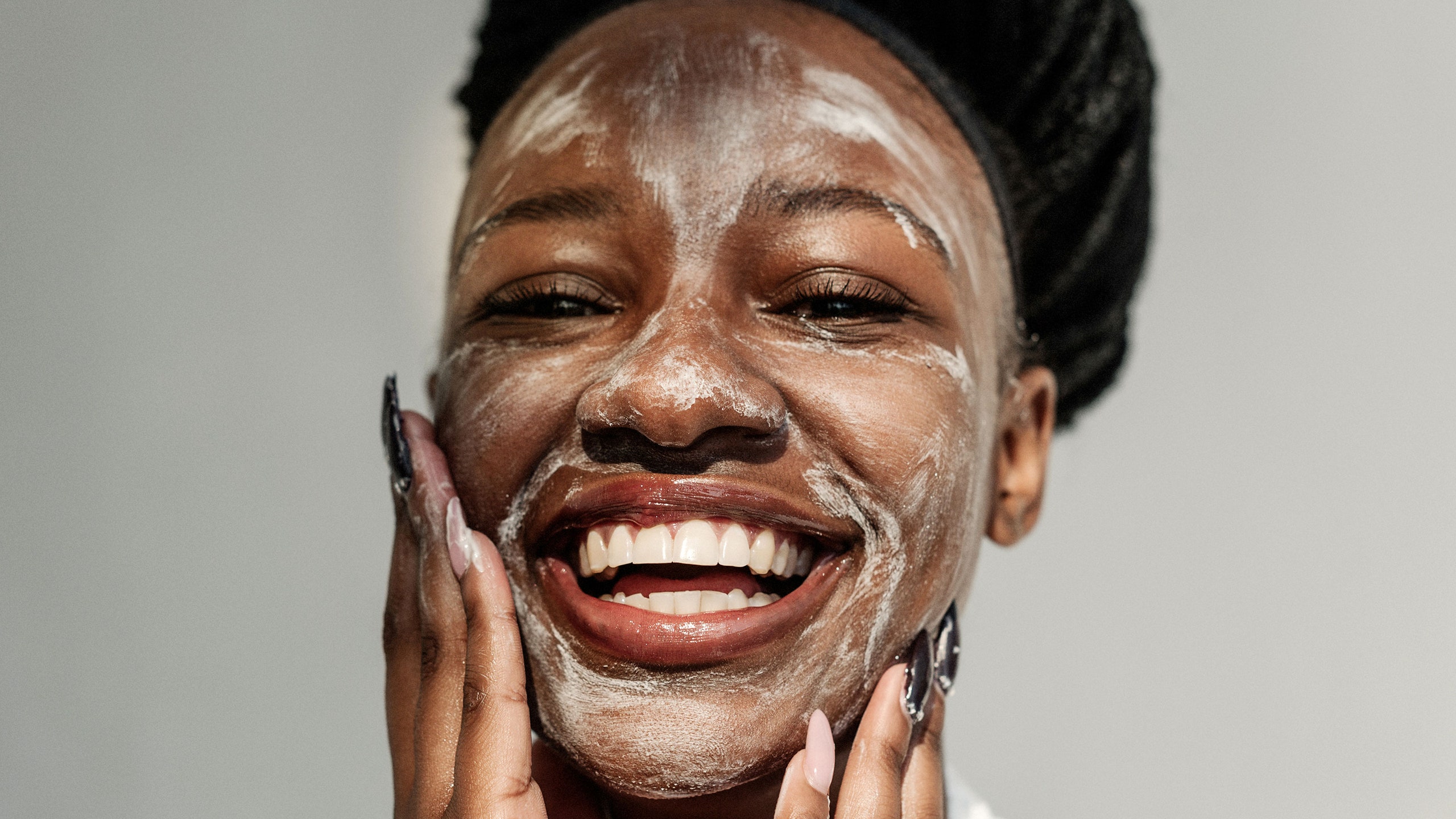 Woman smiling with skincare product on face