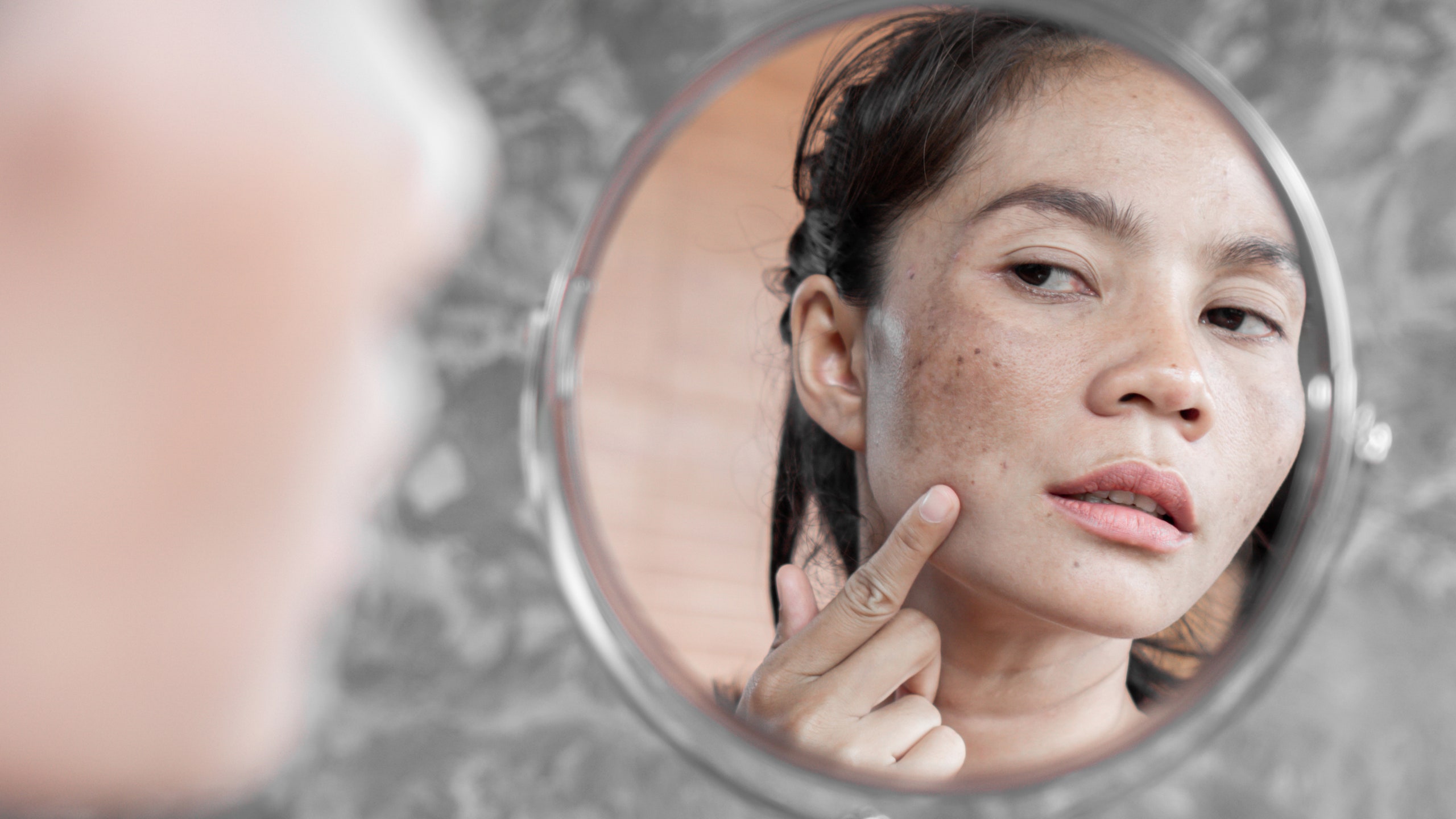 model looking in mirror and examining skin