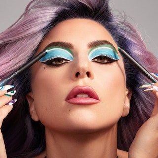Lady Gaga holding eyeliner up to her dramatic blue eye makeup