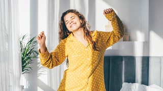 Woman dancing in a pair of yellow printed pajamas for story on the best pajamas for women.