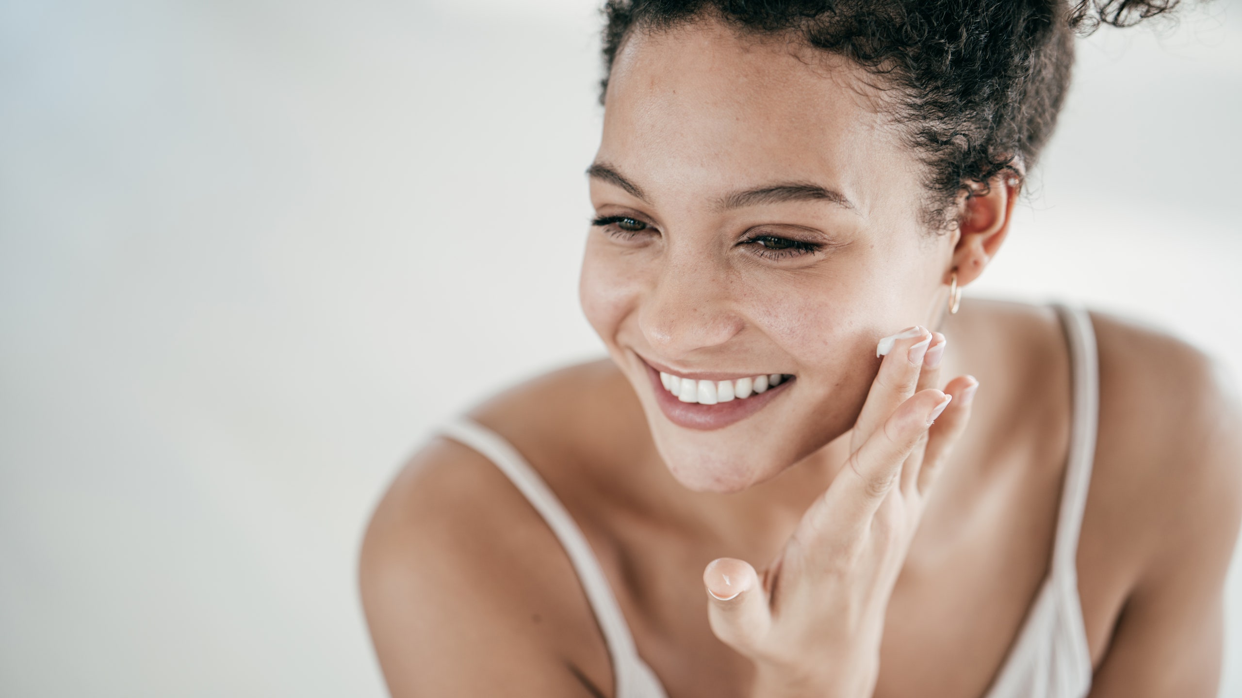 Smiling model in camisole applied face cream