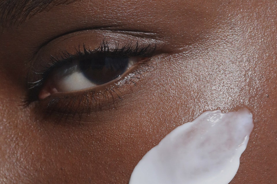 close-up image of woman with face cream on her cheek