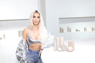 Kim Kardashian appears at a SKKN popup in a metallic look with bright green nails. Her hair is worn long and loose down...