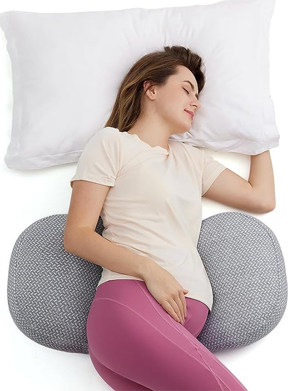 A woman sleeping on the gray Momcozy Pregnancy Wedge Pillow on a white background