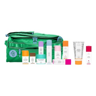 Drunk Elephant Trunk 7.0 array of white skincare products with colorful lids and green cosmetics bag on white background