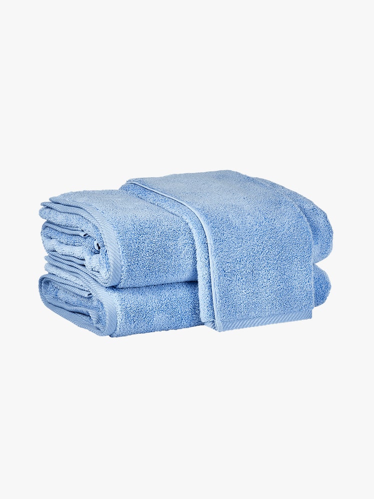 Matouk Milagro Cotton Terry Bath Towel folded blue bath towels on light gray background
