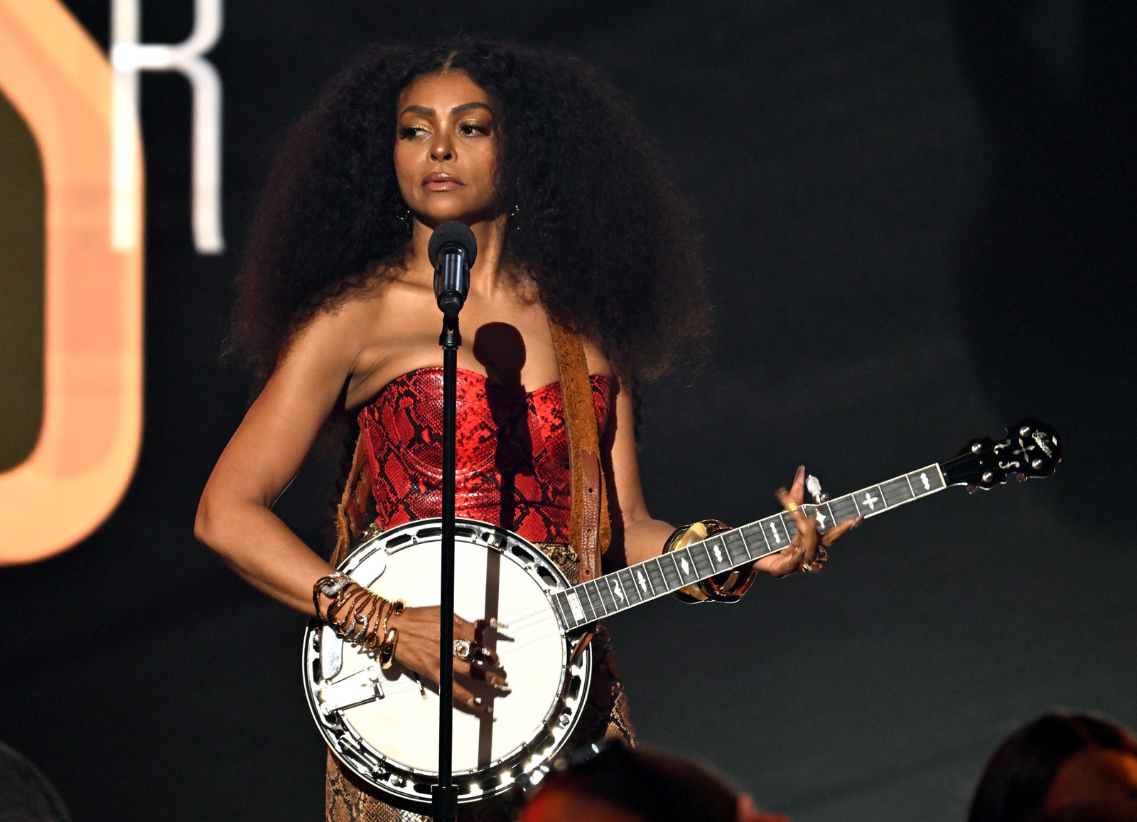 Taraji P. Henson plays a banjo onstage in a red dress.